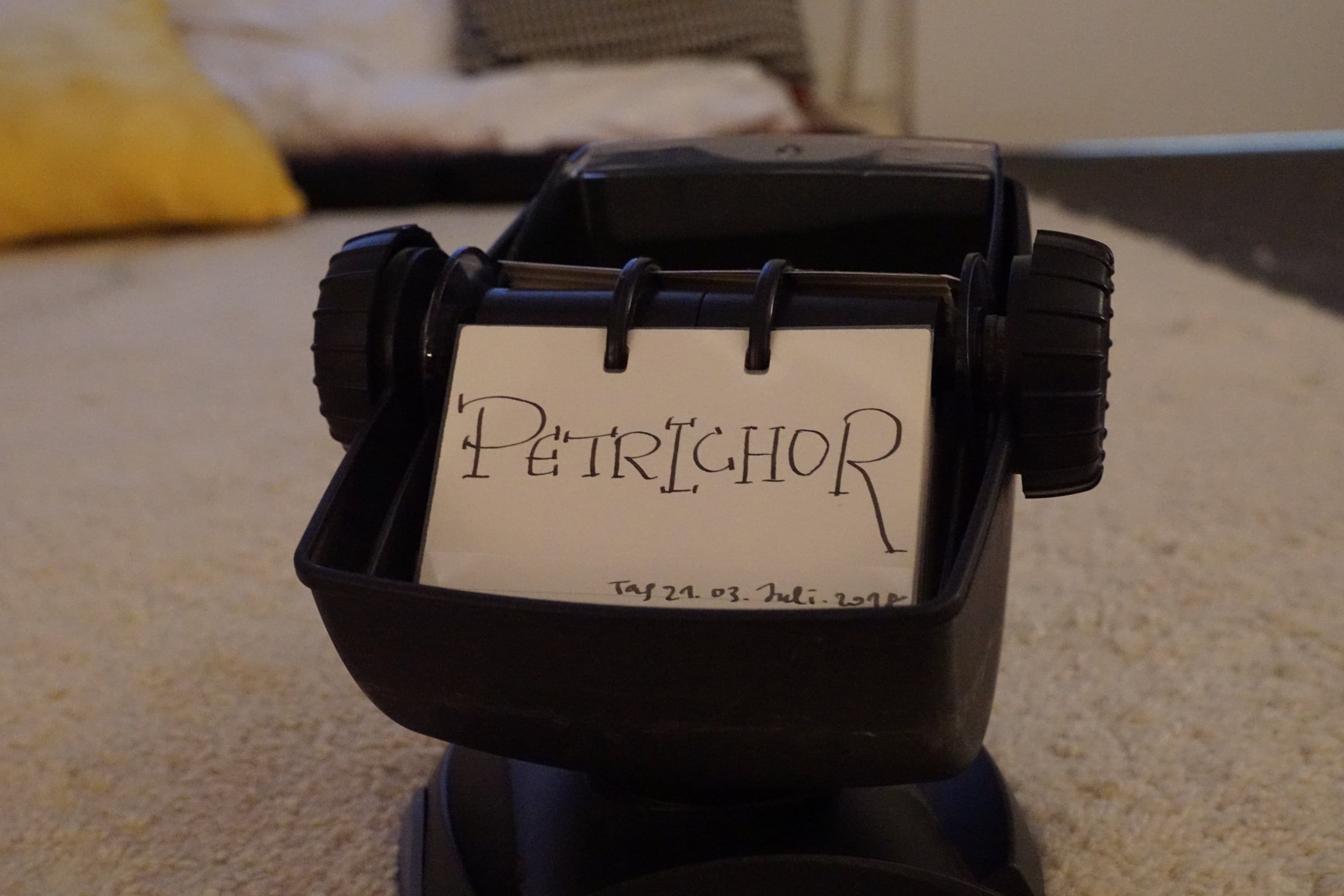 A rotary card file on a carpet, the open card says "Petrichor" in handwriting